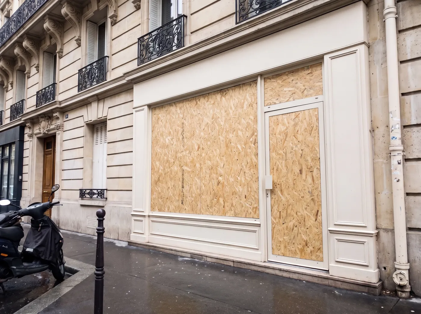 La même boutique, vitrine et porte fermées par des panneaux bois posés par DRM