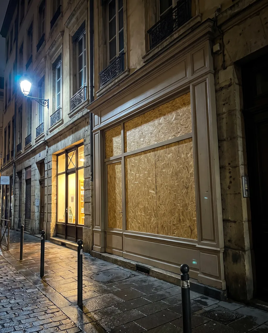 Vitrine d'un bar à jeux lyonnais fermée de nuit par des panneaux bois
